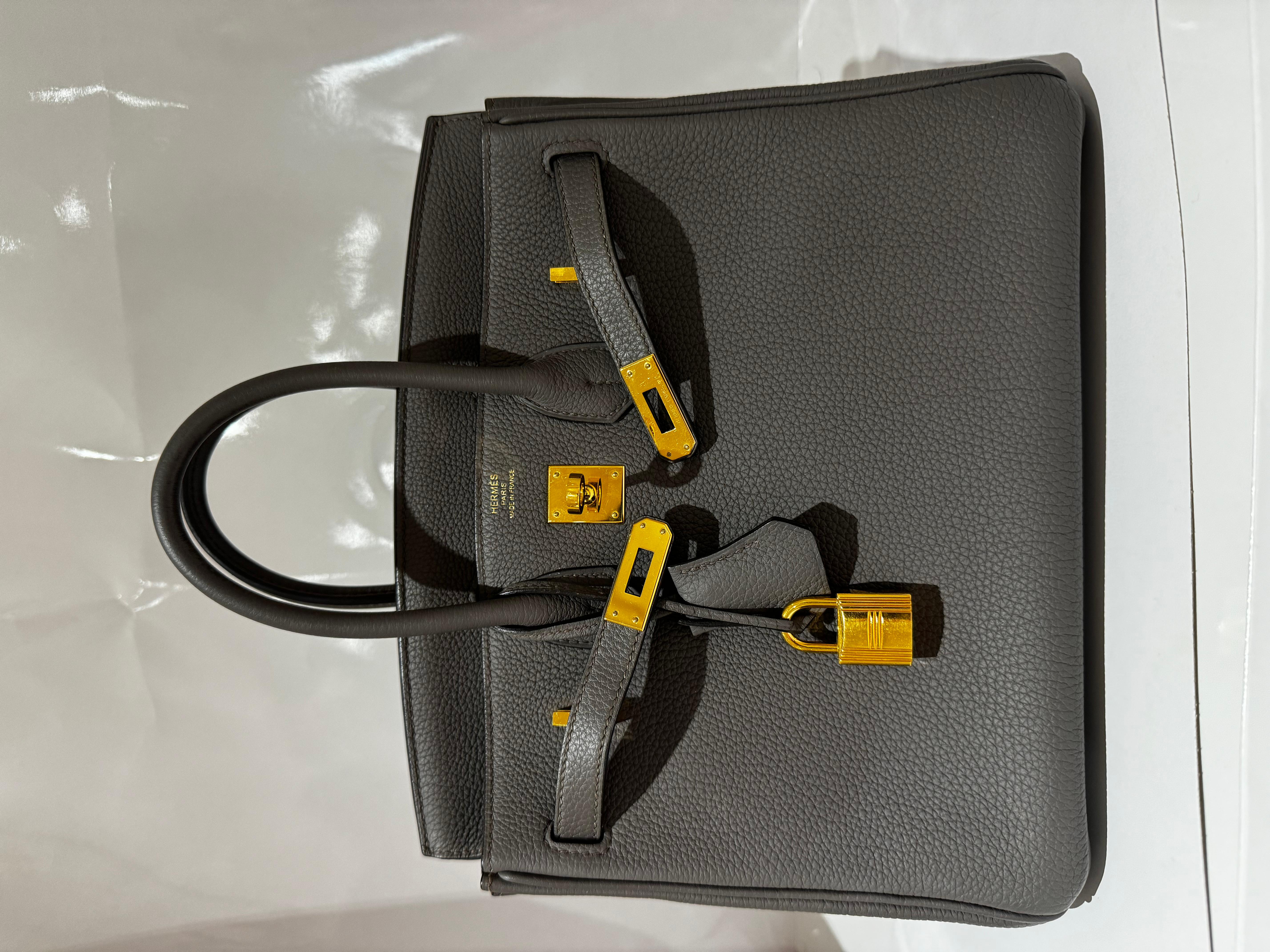 Hermes Birkin 25 in Gris Etain Togo Leather with Gold Hardware handbag. A very classic combo.

Grey grained semi matte finish leather exterior, two top handles. Comes with dustbag and clochette, lock and keys. Very good condition, only few signs in