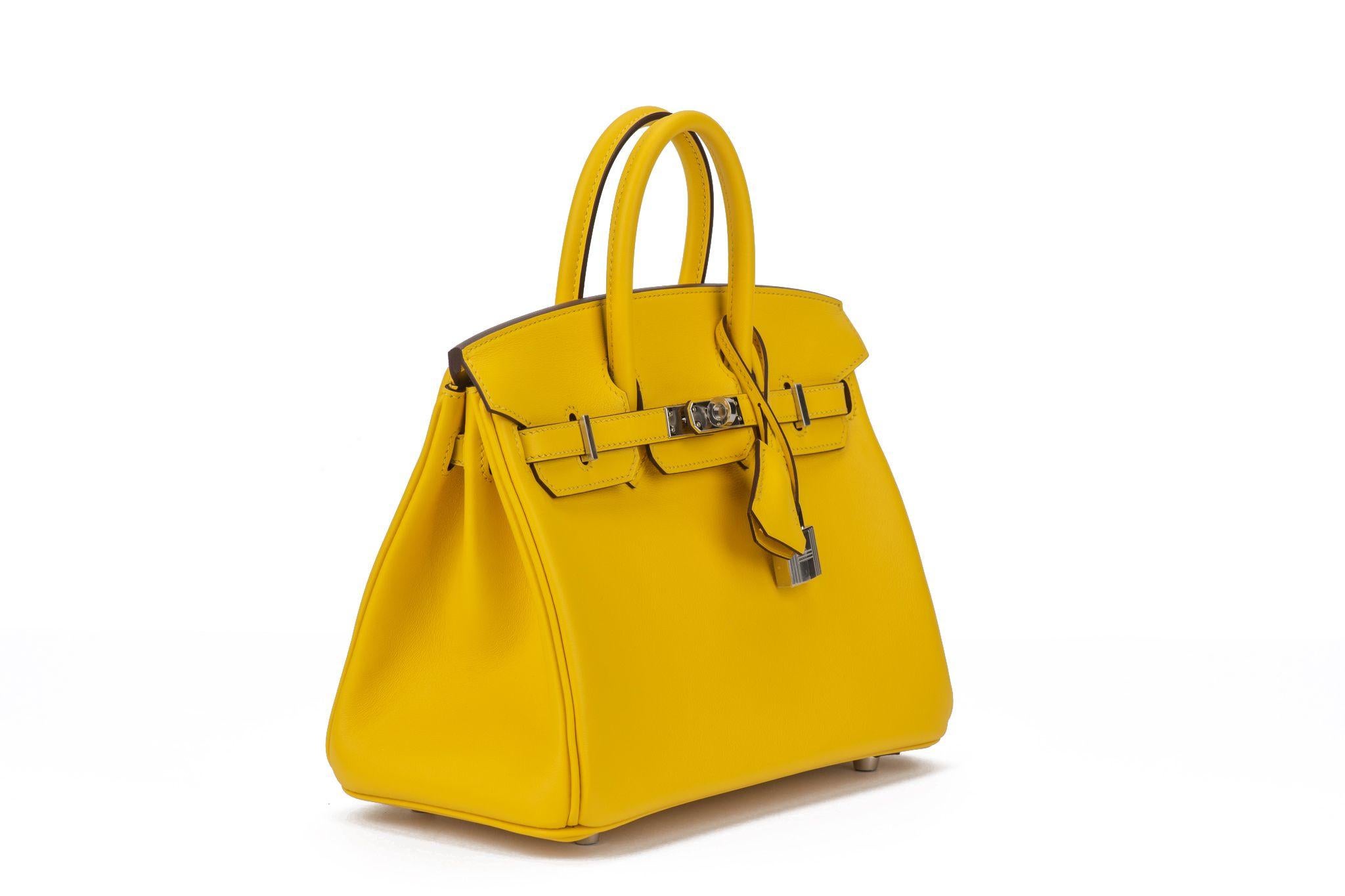 Hermès Birkin 25 bag made of swift leather in Jaune Naples color. The bag comes with silver palladium hardware. Date stamp B for 2023.  The item is new and comes with the original clochette, tirette, lock, 2 keys, dust cover, rain jacket, box.