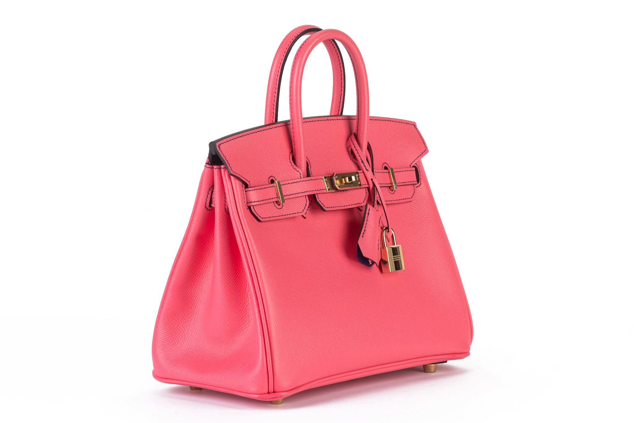 This Birkin 25 verso limited edition features a epsom leather in rose d'ete` with rolled leather handles, a front flap with turn-lock closure, gold hardware, and interior zip and slip pockets. The interior is lined with chèvre electric blue leather.