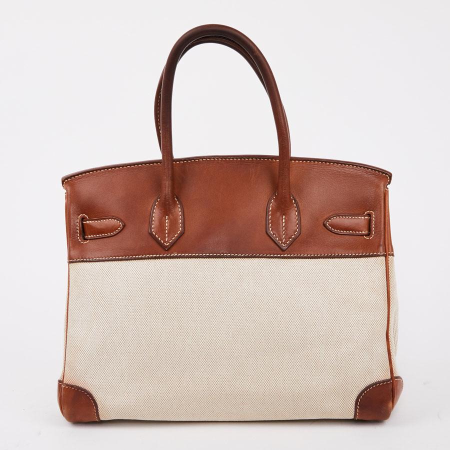 HERMES Birkin 30 canvas / dual-material leather bag:
This iconic second-hand HERMES Birkin handbag is in beige canvas and brown Barenia leather. The topstitching is beige. It has its zipper, bell, keys (two) and padlock. The jewelry is made of