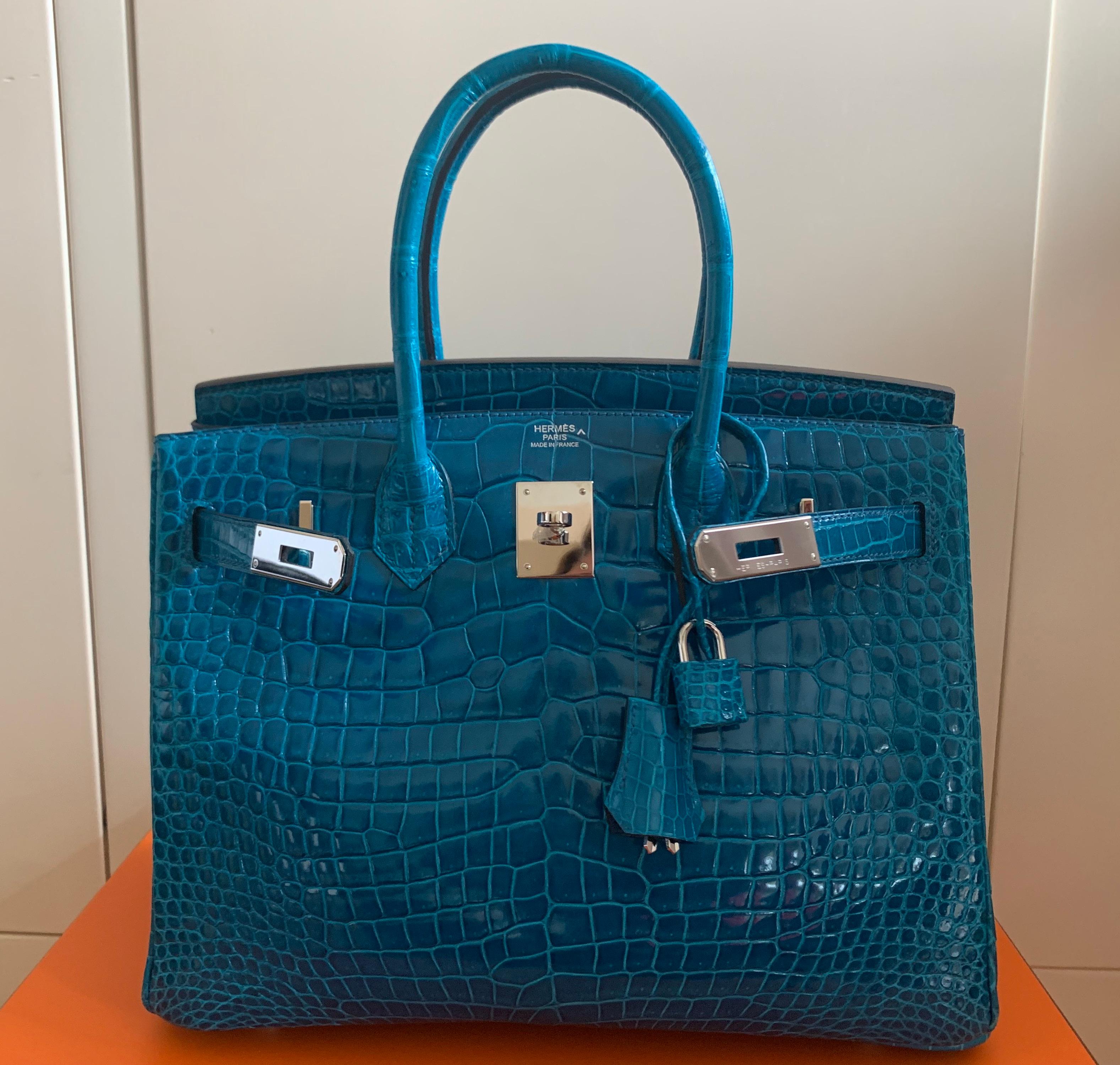 Birkin 30 blue Izmir croco shiny Porosus. Highly collectible.
Very rare colour, blue like Caribbean deep sea
Two rolled top handles
Palladium plated Hardware
Internal zip and slip pocket   2014 letter R  in square 
Condition  Mint 
pre owned but