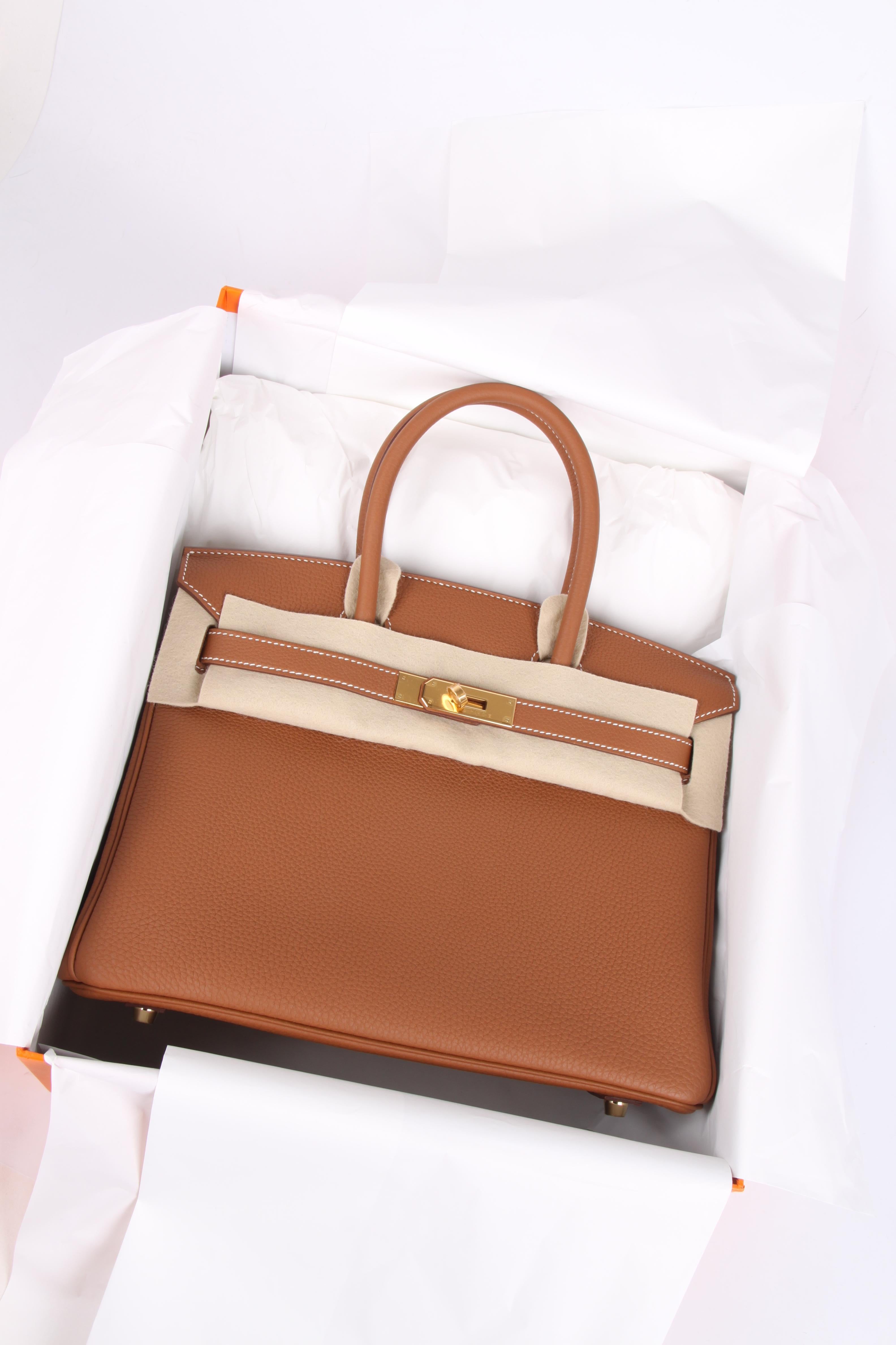 This bag is brand new and is absolutely gorgeous; a Hermès Birkin Bag 30 in Togo leather with gold hardware.

Front toggle closure, clochette with lock and two keys, and double rolled handles. The Togo leather has a visible grain, is supple and yet