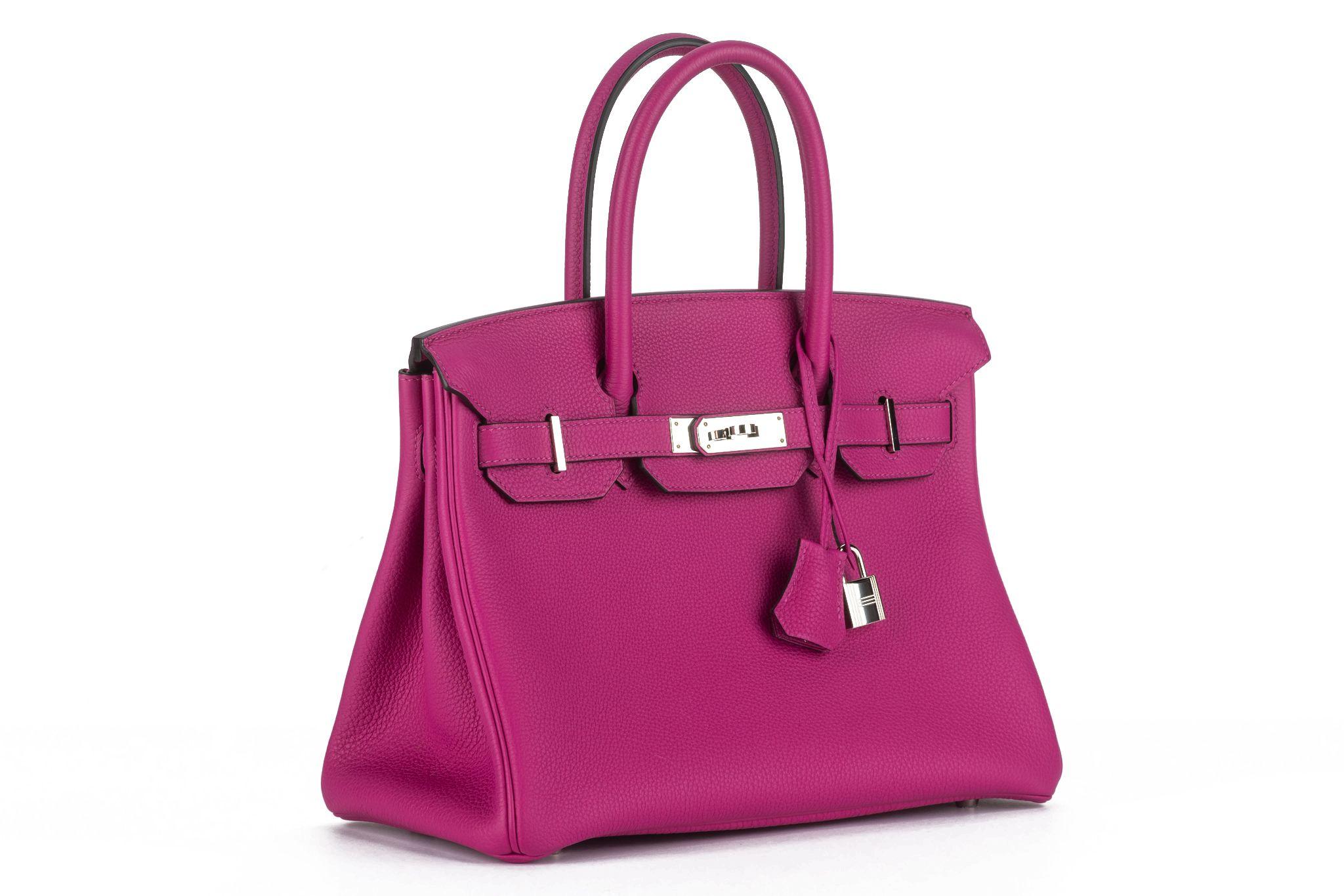 The Birkin 30 Togo magenta with palladium hardware, having tonal stitching, front flap, two straps with center toggle closure, clochette with lock and two keys, and double rolled handles. The interior is lined with chevre leather. Comes with a
