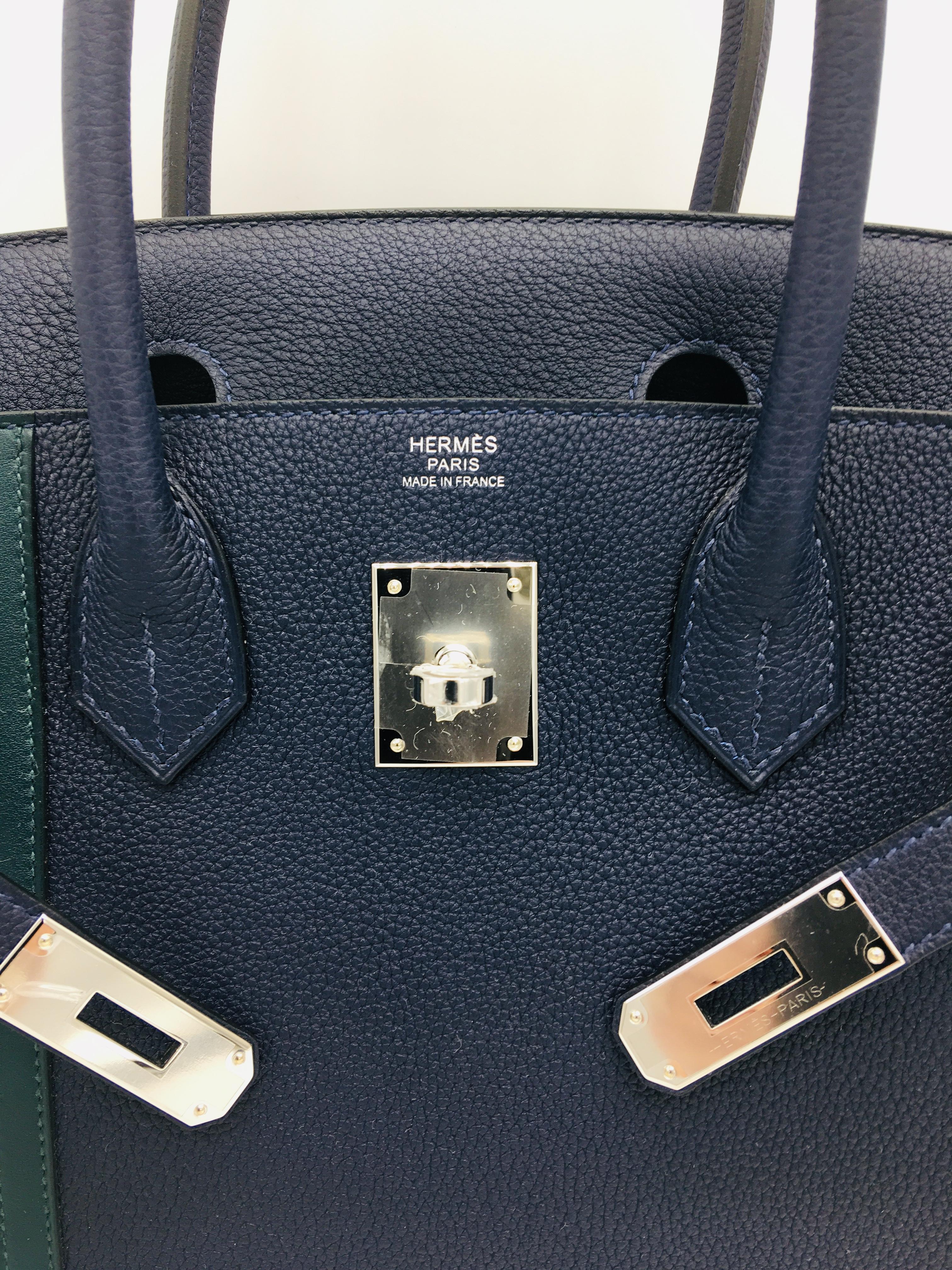 This unusual Birkin Officier in dark Bleu Nuit features two stripes in Vert Cypress to one side of the bag adding a distinctive touch to the classic Birkin.  The main body of the bag is in Togo Leather  with the contrasting stripes in Swift, with