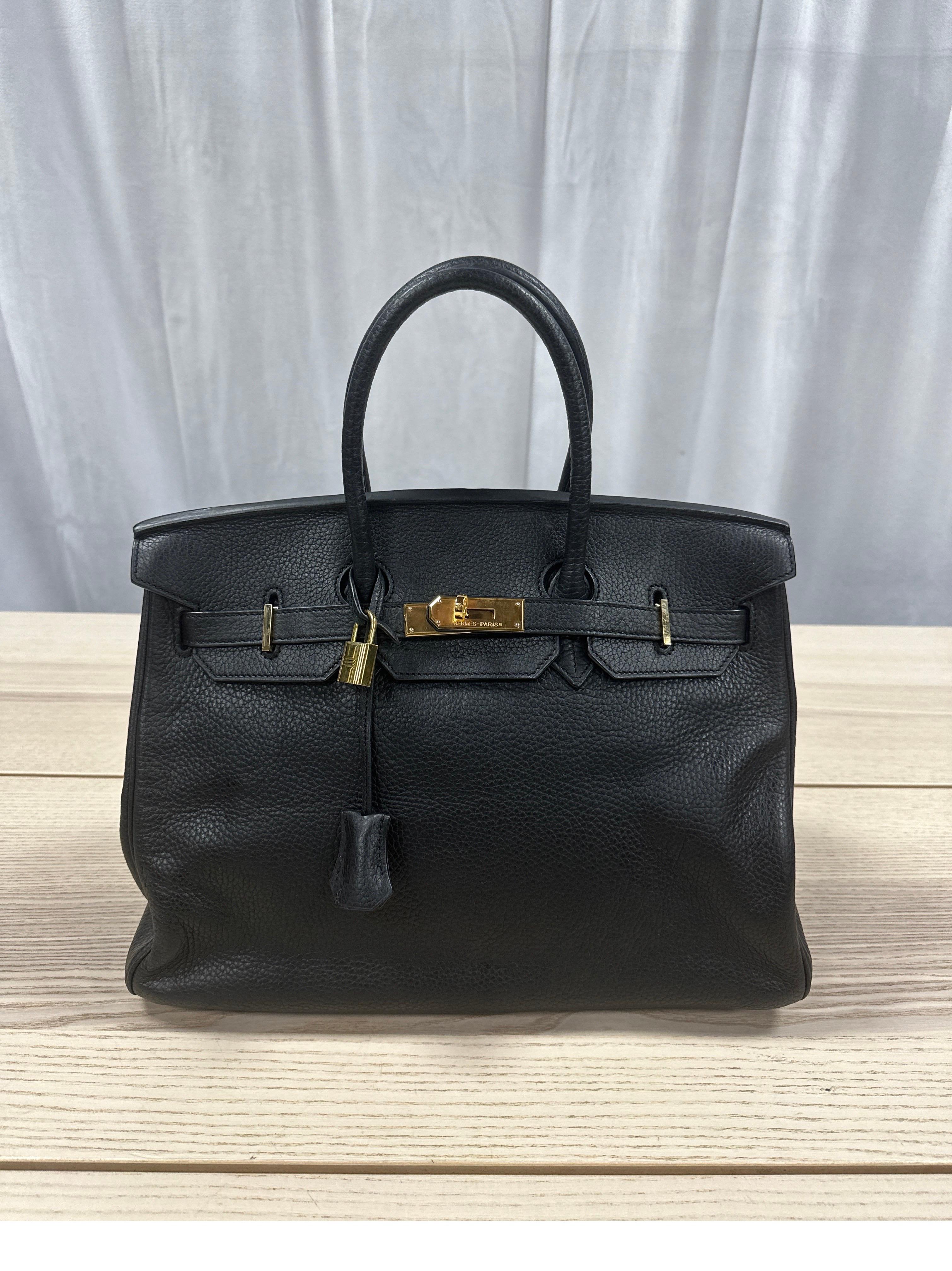 This is an authentic HERMES Ardennes Birkin 35 in NOIR. This stunning handbag is crafted of grained leather in BLACK. The bag features thin but sturdy rolled leather top handles, a crossover flap with a strap closure, clasps with a gold plated