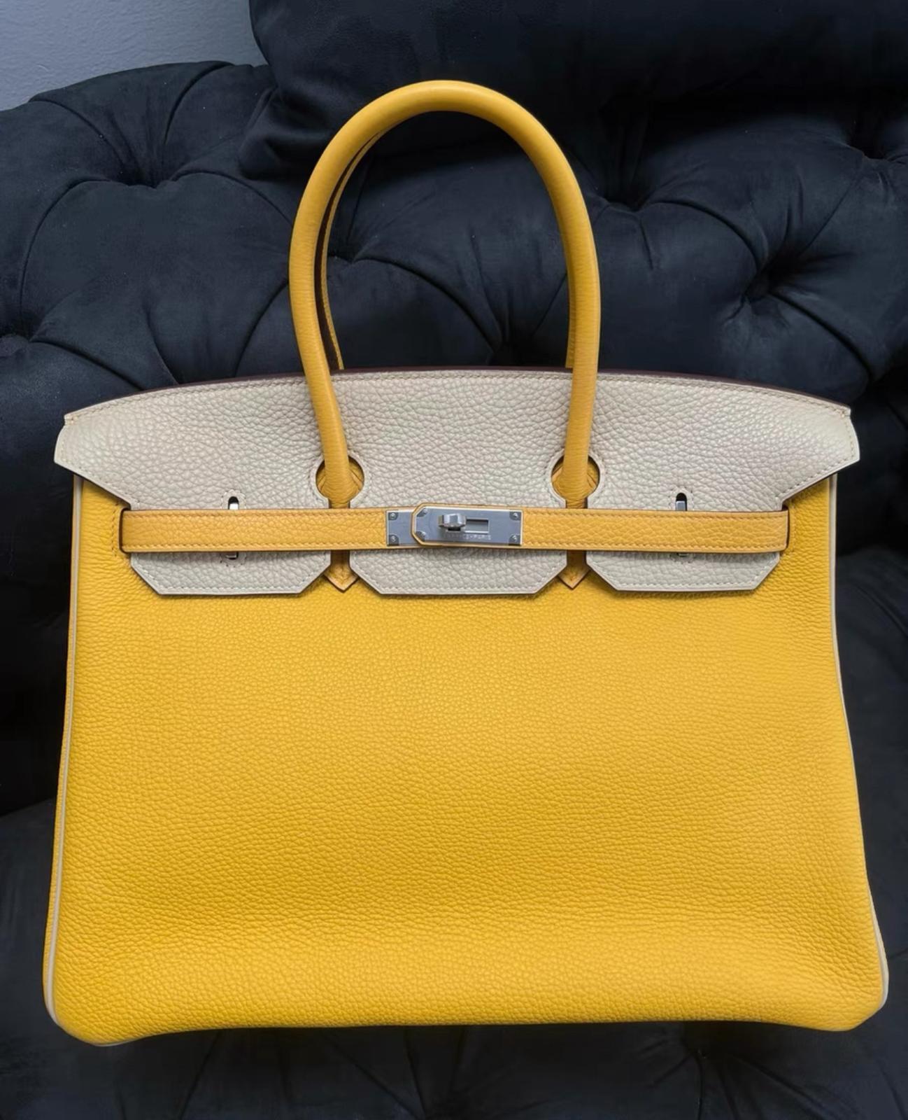 Questa Birkin 35 è in pelle Jaune Ambre e Craie togo con finiture in palladio argento e presenta cuciture tonali, patta frontale, due cinturini con chiusura centrale ad alamari, clochette con lucchetto e due chiavi e doppi manici