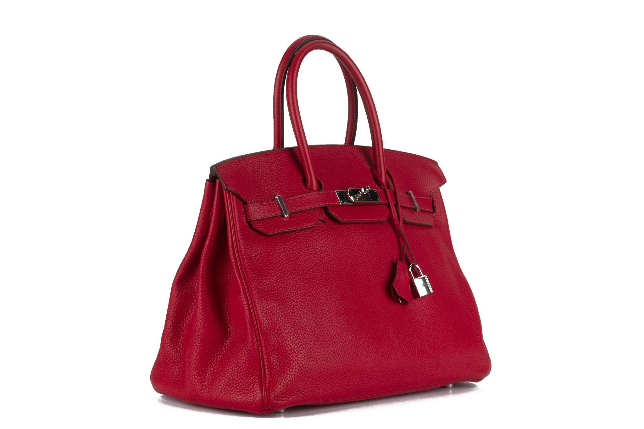 The Birkin 35 in rouge vif taurillon clemence leather with palladium hardware and has tonal stitching, front flap, two straps with center toggle closure, clochette with two keys and double rolled handles. The interior is lined with chevre leather.