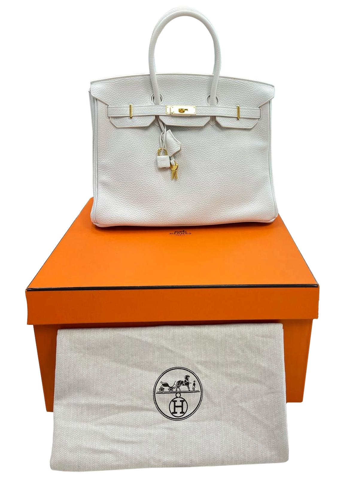 This Birkin is in White clemence leather with gold hardware and has tonal stitching, a front toggle closure, a clochette with lock and two keys, and double rolled handles. The interior is lined with White chevre and has one zip pocket with an Hermès