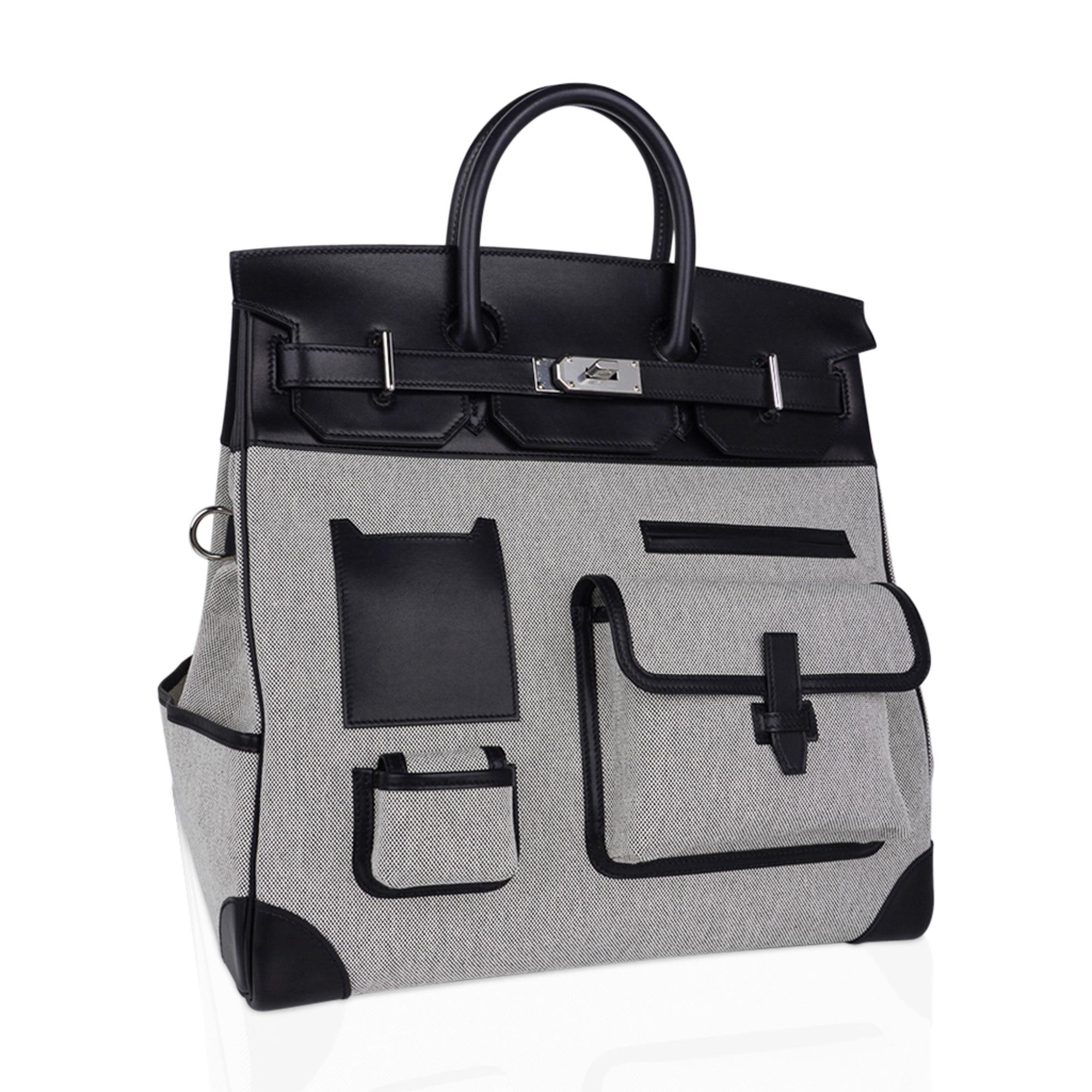 Mightychic offers a very rare Hermes Cargo Birkin HAC 40 bag featured in Black Evercalf leather and Toile H in Ecru and Noir.
Added exterior pockets, cup holder, D ring and clips bring a fresh take to this iconic bag.
This fresh, functional Hermes