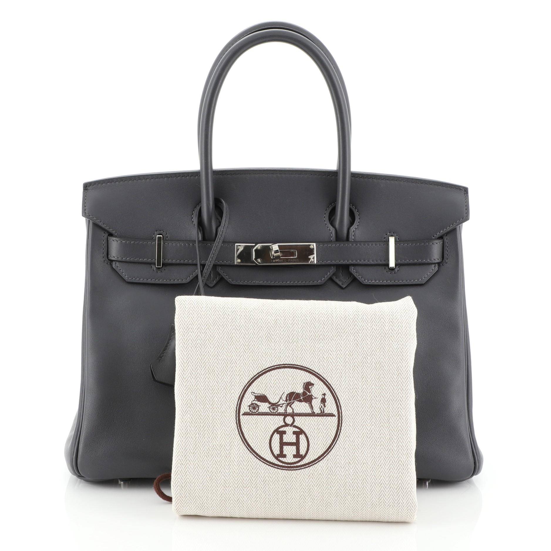 This Hermes Birkin Handbag Ardoise Swift with Palladium Hardware 30, crafted in Ardoise grey Swift leather, features dual rolled top handles, frontal flap, and palladium hardware. Its turn-lock closure opens to an Ardoise grey Swift leather interior