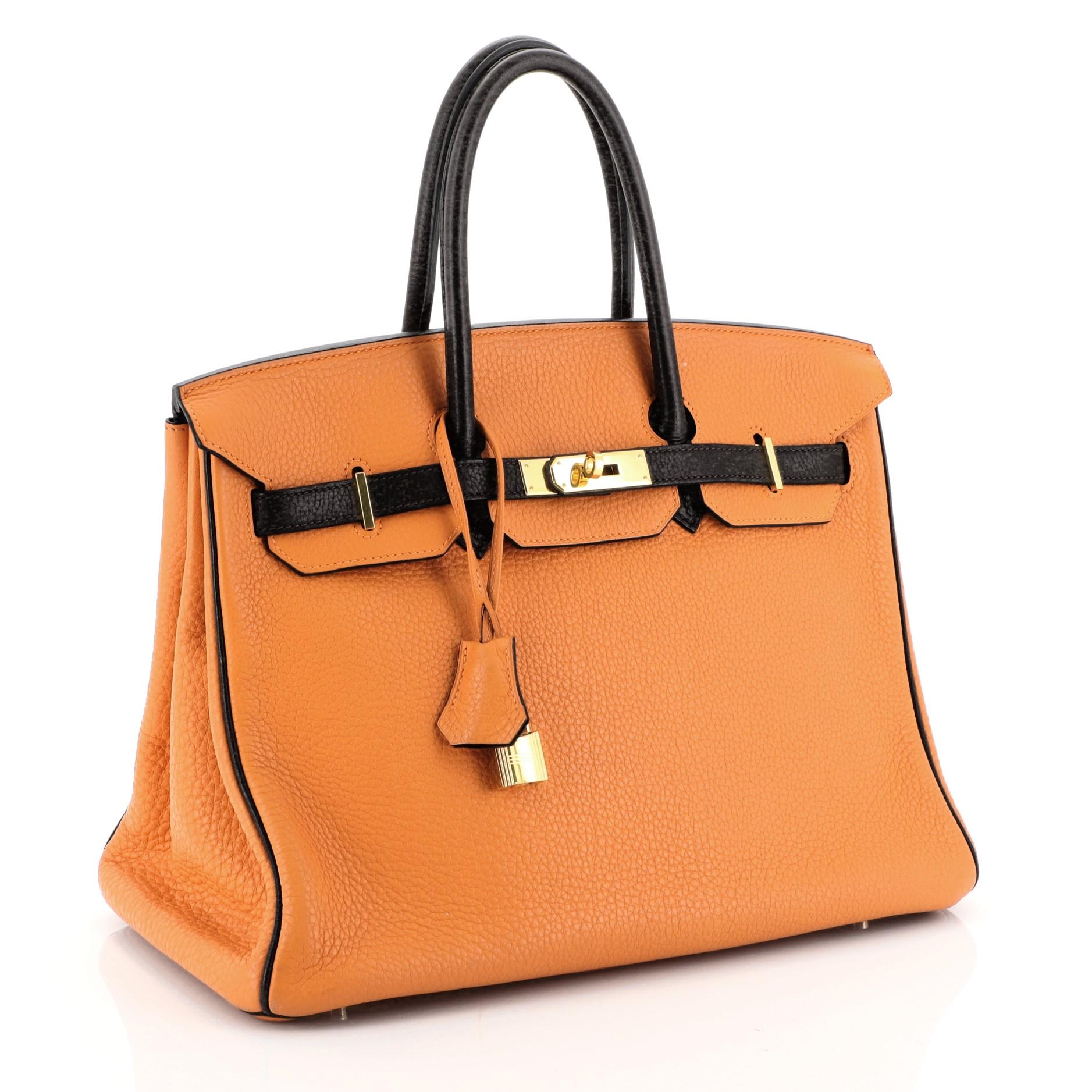 This Hermes Birkin Handbag Bicolor Clemence With Gold Hardware 35, crafted in Orange H and Ebene Clemence leather, features dual rolled handles, frontal flap, and gold hardware. Its turn-lock closure opens to an Ebene Chevre leather interior with