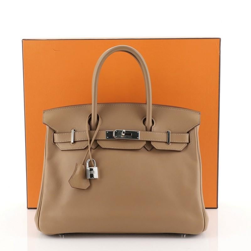 This Hermes Birkin Handbag Biscuit Swift with Palladium Hardware 30, crafted in Biscuit brown Swift leather, features dual rolled handles, frontal flap, and palladium hardware. Its turn-lock closure opens to a Biscuit brown Swift leather interior
