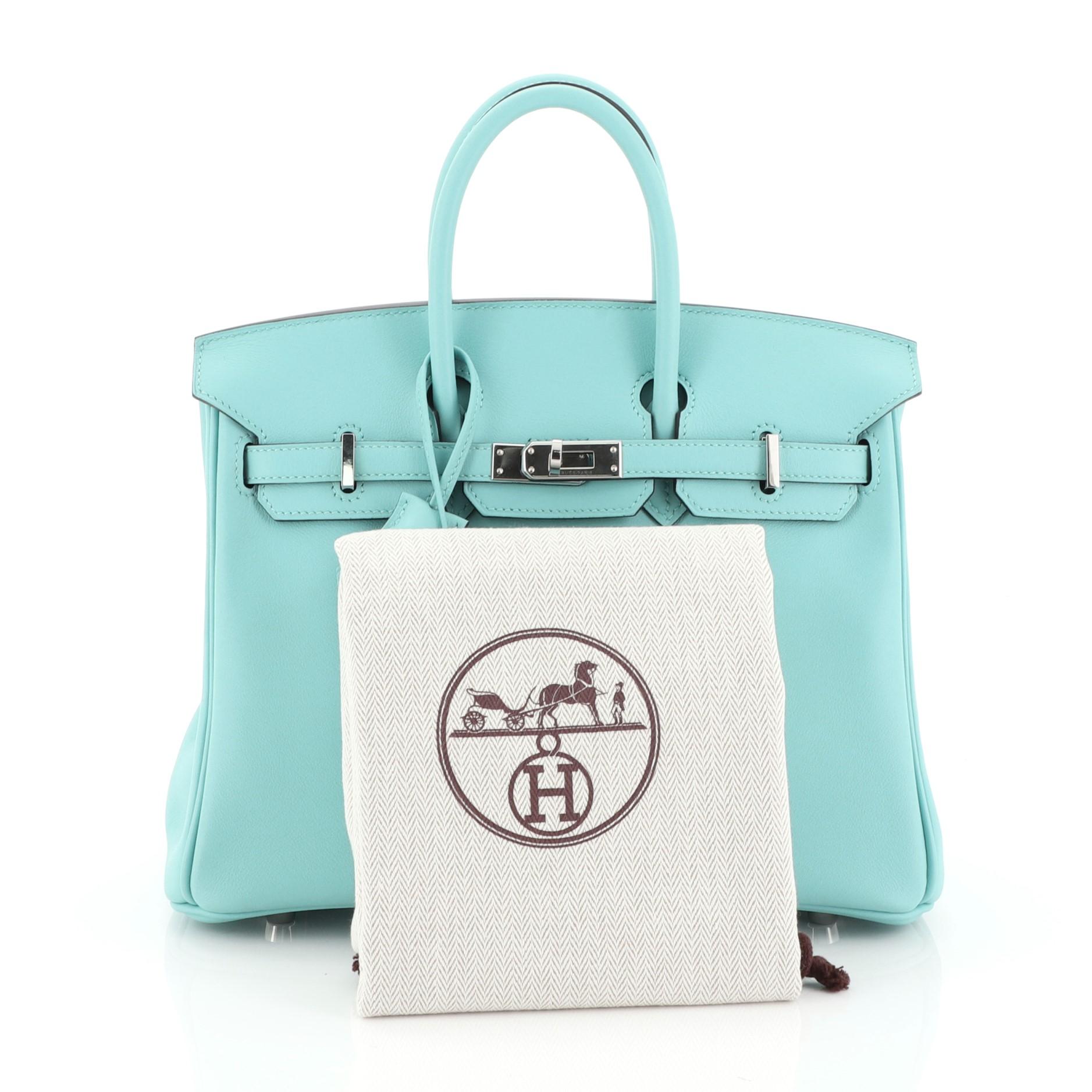This Hermes Birkin Handbag Bleu Atoll Swift with Palladium Hardware 25, crafted in Bleu Atoll blue Swift leather, features dual rolled handles, frontal flap, and palladium hardware. Its turn-lock closure opens to a Bleu Atoll blue Swift leather
