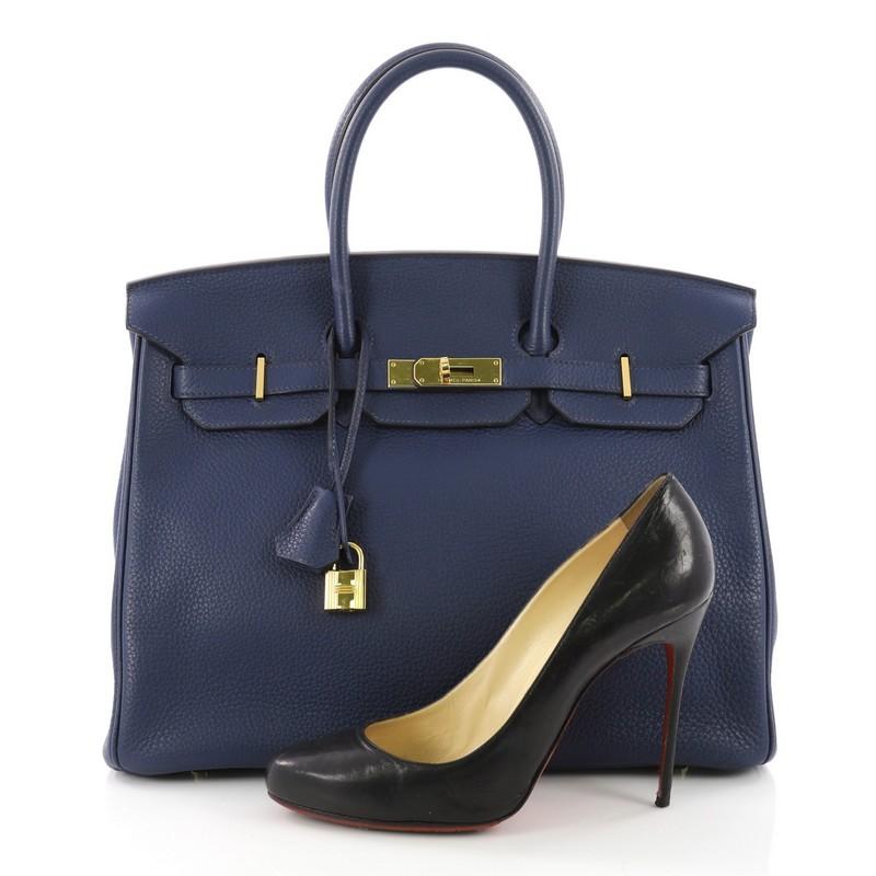 This Hermes Birkin Handbag Bleu Saphir Clemence with Gold Hardware 35, crafted Bleu Saphir clemence leather, features dual rolled top handles, frontal flap, and gold-tone hardware. Its turn-lock closure opens to a blue leather interior with slip and