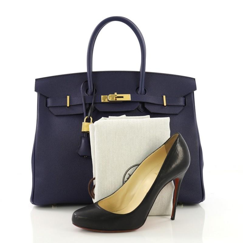 This Hermes Birkin Handbag Bleu Saphir Epsom with Gold Hardware 35, crafted in Bleu Saphir Epsom leather, features dual rolled handles, frontal flap, and gold hardware. Its turn-lock closure opens to a Bleu Saphir Chevre leather interior with slip