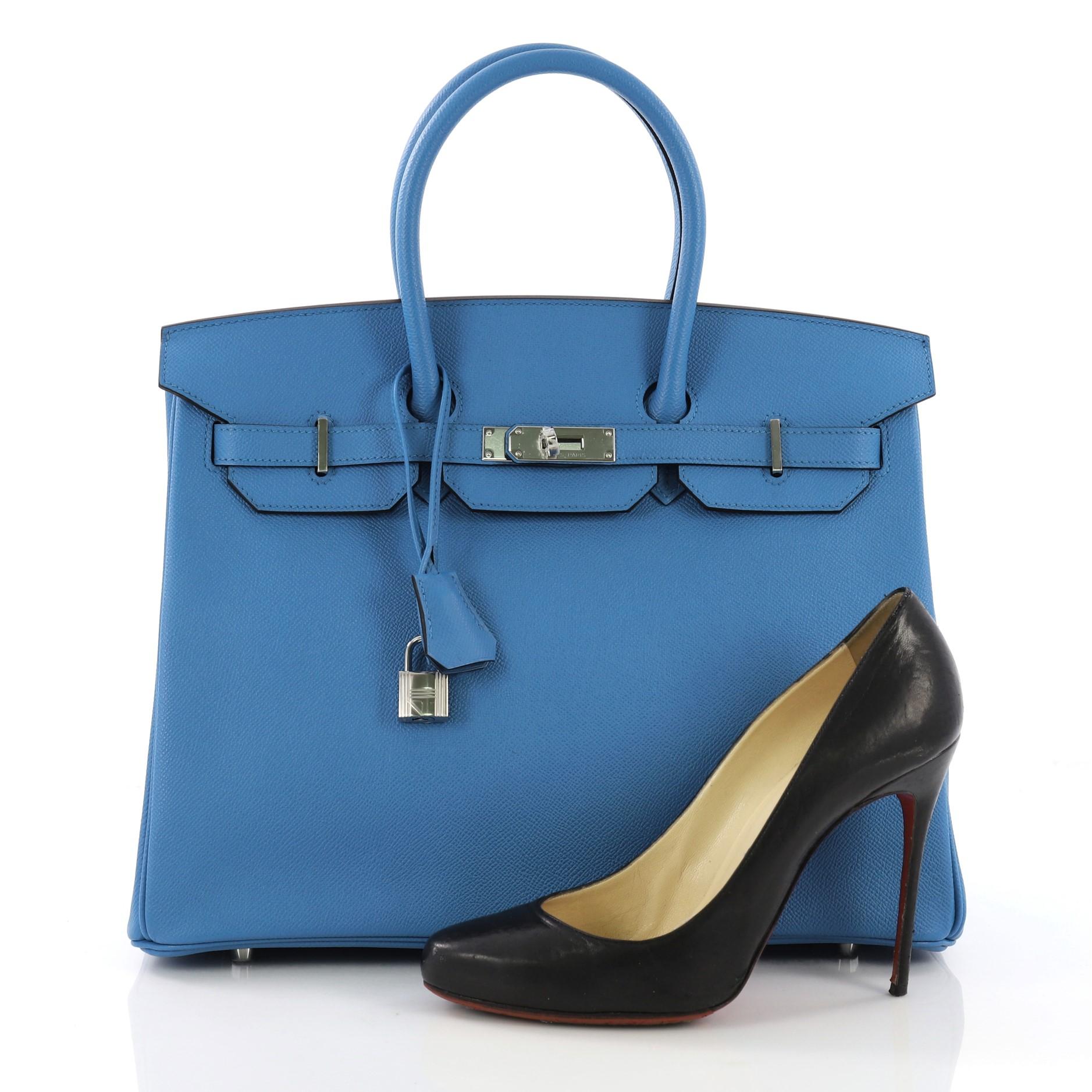 This Hermes Birkin Handbag Bleu Zanzibar Epsom with Palladium Hardware 35, crafted in Bleu Zanzibar blue Epsom leather, features dual rolled handles, frontal flap and palladium hardware. Its turn-lock closure opens to a Bleu Zanzibar blue Chevre
