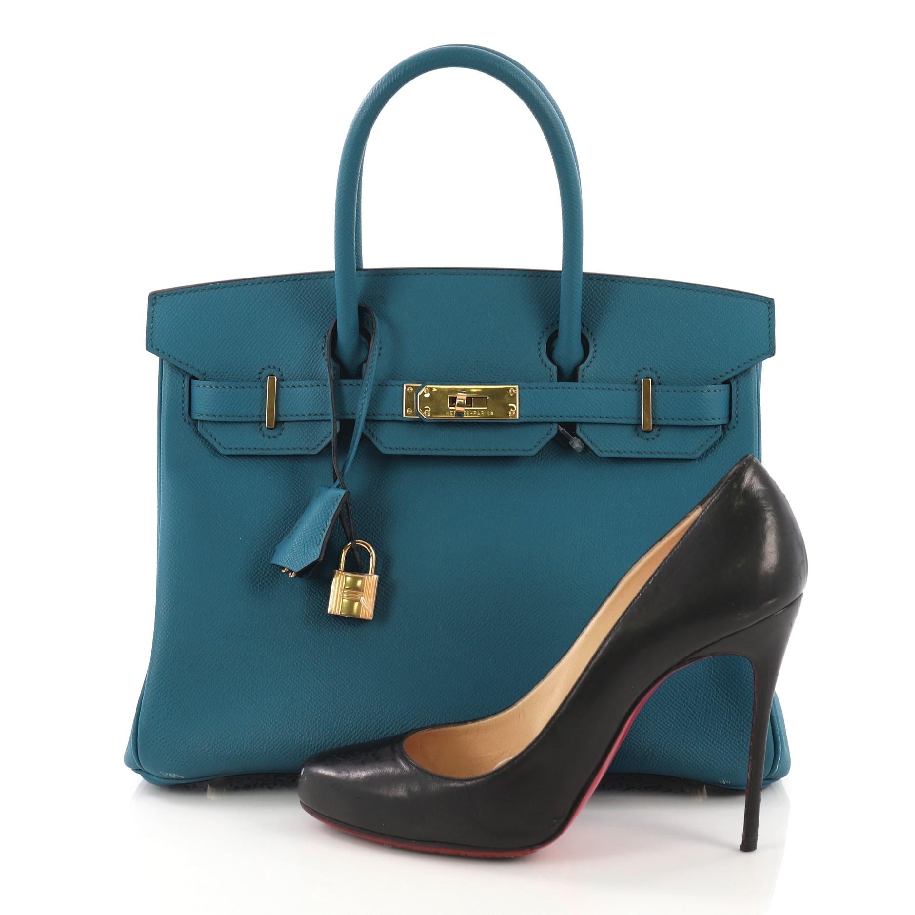 This Hermes Birkin Handbag Blue Izmir Epsom with Gold Hardware 30, crafted in Blue Izmir blue Epsom leather, features dual rolled top handles, a frontal flap, and gold hardware. Its turn-lock closure opens to a Blue Izmir blue Chevre leather