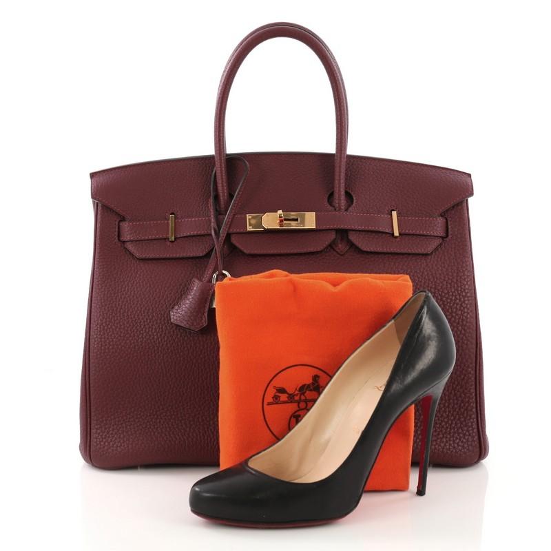 This Hermes Birkin Handbag Bordeaux Togo with Gold Hardware 35, crafted in Bordeaux red Fjord leather, features dual rolled top handles, protective base studs, and gold-tone hardware. Its turn-lock closure opens to a red leather interior with zip