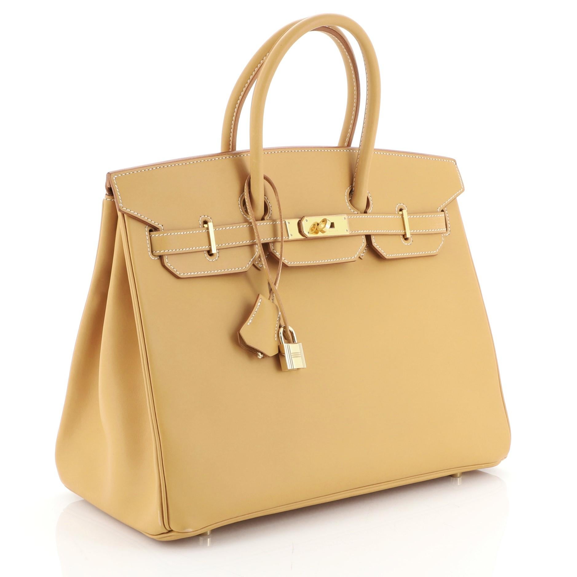 This Hermes Birkin Handbag Brown Vache Natural with Gold Hardware 35, crafted in Natural neutral Vache Natural leather, features dual rolled handles, frontal flap, and gold hardware. Its turn-lock closure opens to a Natural neutral Chevre leather