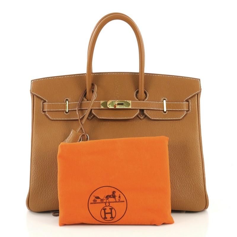 This Hermes Birkin Handbag Caramel Chevre de Coromandel with Gold Hardware 35, crafted in Caramel brown Chevre de Coromandel leather, features dual rolled handles, frontal flap, and gold hardware. Its turn-lock closure opens to a Caramel brown