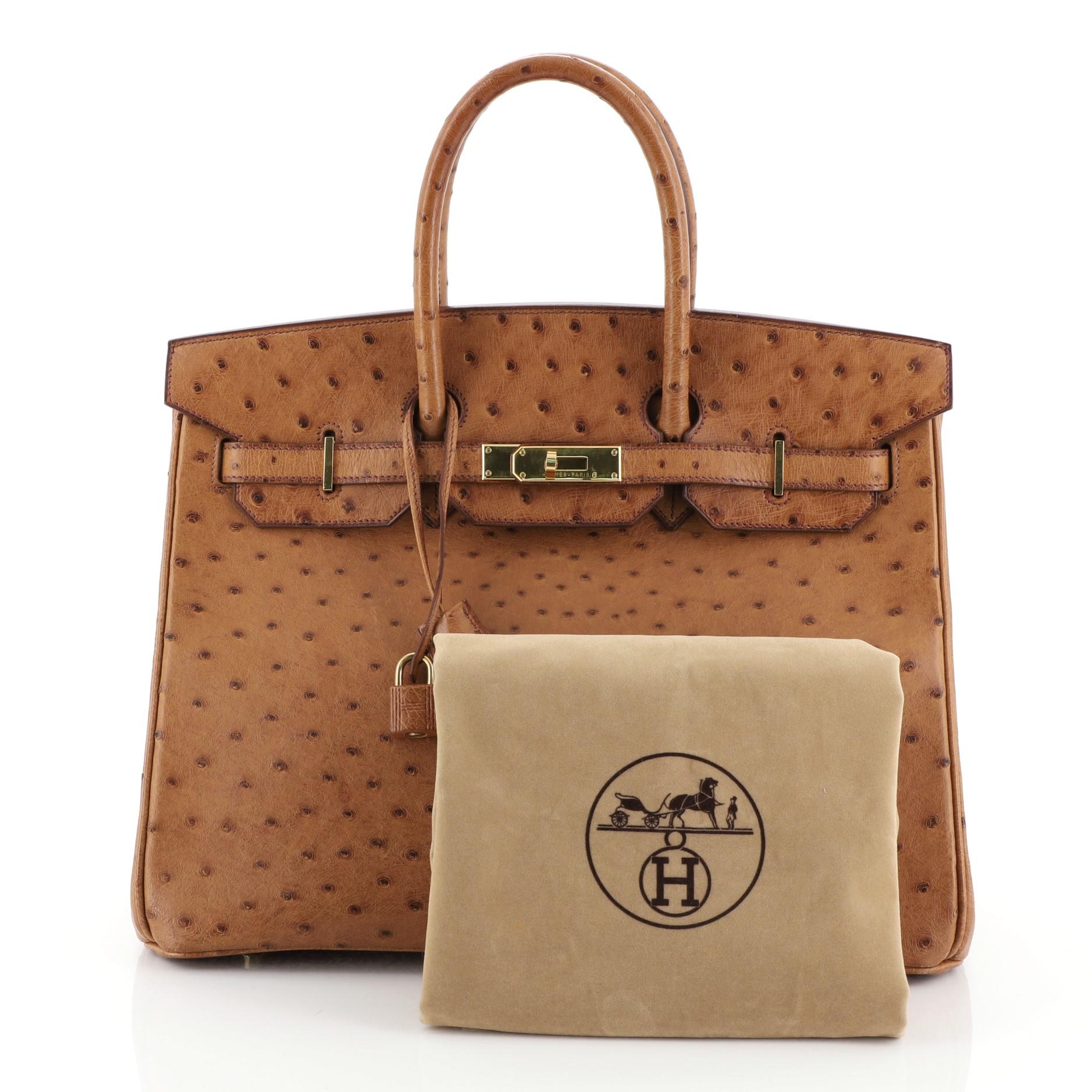 This Hermes Birkin Handbag Cognac Ostrich with Gold Hardware 35, crafted in genuine Cognac brown Ostrich, features dual rolled top handles, frontal flap, and gold hardware. Its turn-lock closure opens to a Cognac brown Chevre leather interior with