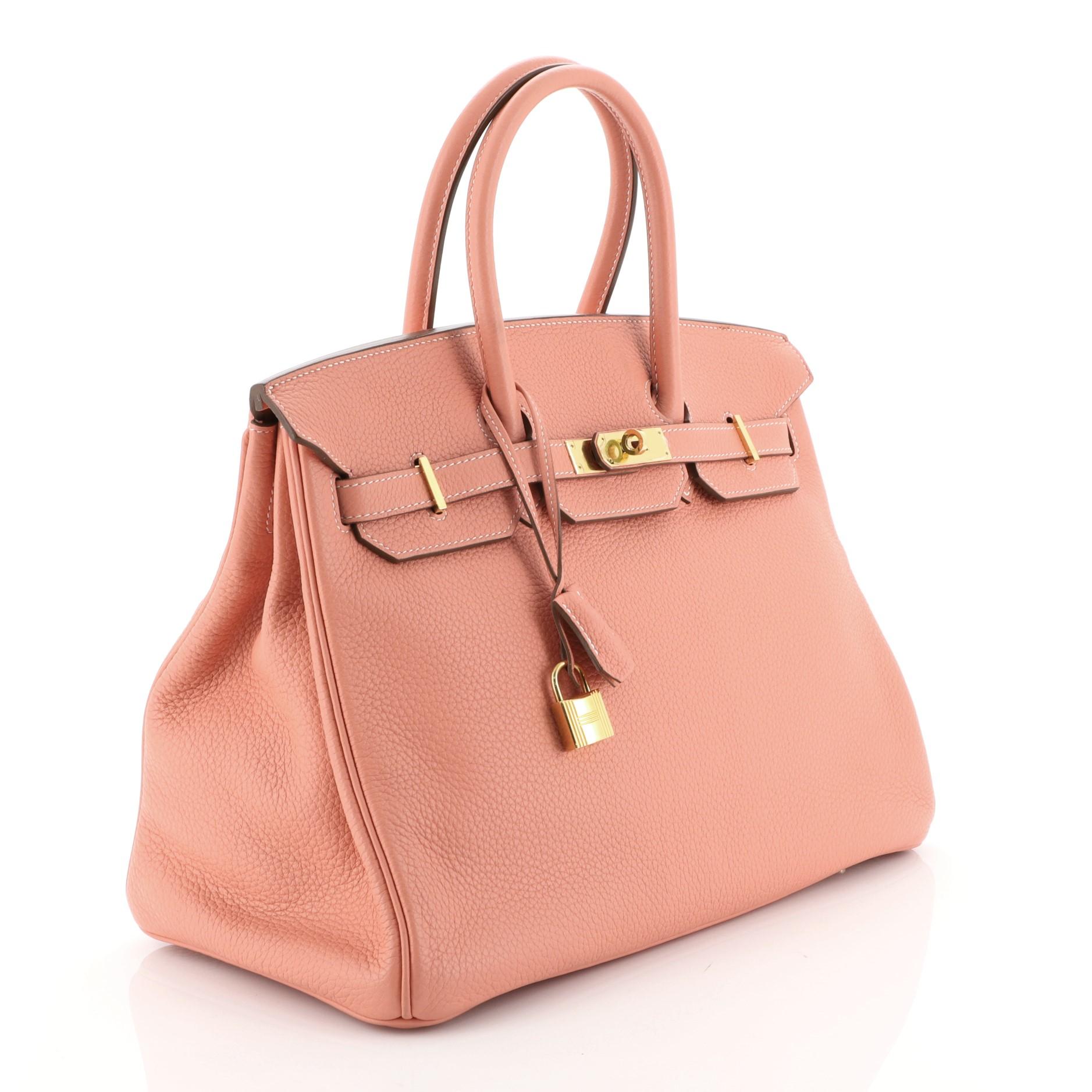 This Hermes Birkin Handbag Crevette Clemence with Gold Hardware 35, crafted in Crevette pink Clemence leather, features dual rolled handles, frontal flap, and gold hardware. Its turn-lock closure opens to a Crevette pink Chevre leather interior with