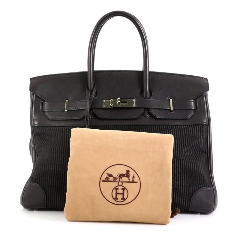 This Hermes Birkin Handbag Crinoline and Noir Barenia with Palladium Hardware 35, crafted in Noir black Barenia leather and Crinoline fabric, features dual rolled top handles, frontal flap, and palladium hardware. Its turn-lock closure opens to a