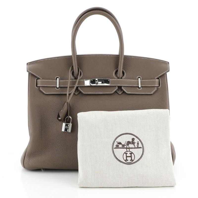 This Hermes Birkin Handbag Etoupe Clemence with Palladium Hardware 35, crafted in Etoupe neutral Clemence leather, features dual rolled handles, frontal flap, and palladium hardware. Its turn-lock closure opens to a Etoupe neutral leather interior