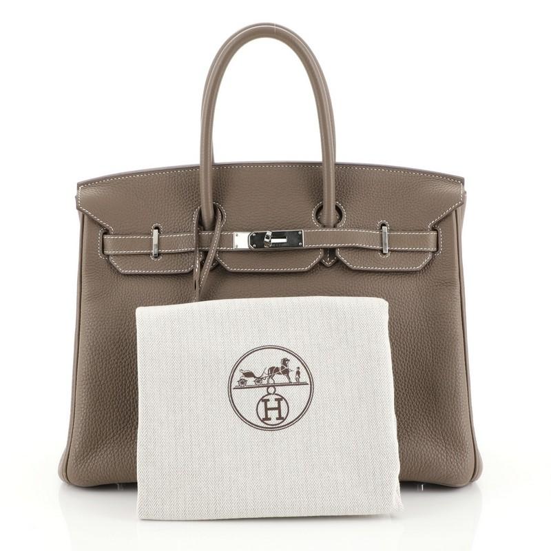 This Hermes Birkin Handbag Etoupe Togo with Palladium Hardware 35, crafted in Etoupe neutral Togo leather, features dual rolled top handles, frontal flap, and palladium hardware. Its turn-lock closure opens to an Etoupe neutral Chevre leather