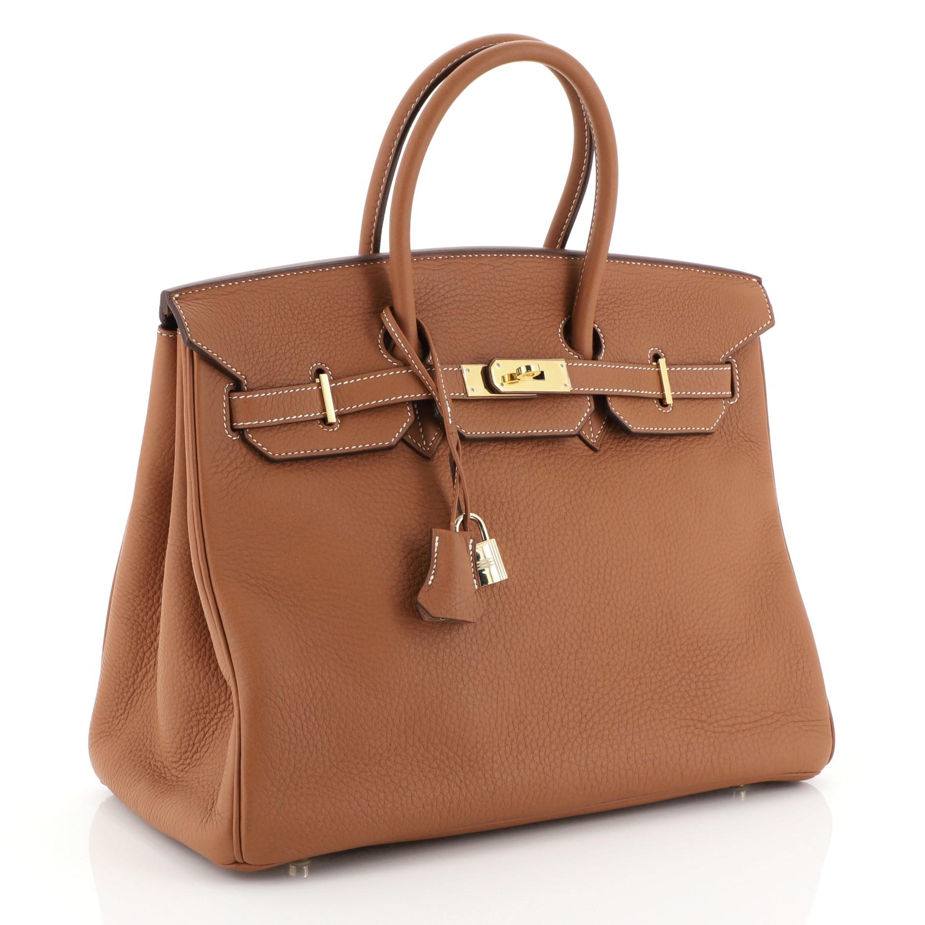 This Hermes Birkin Handbag Etrusque Clemence with Gold Hardware 35, crafted in Etrusque brown Clemence leather, features dual rolled handles, frontal flap, and gold hardware. Its turn-lock closure opens to an Etrusque brown Chevre leather interior