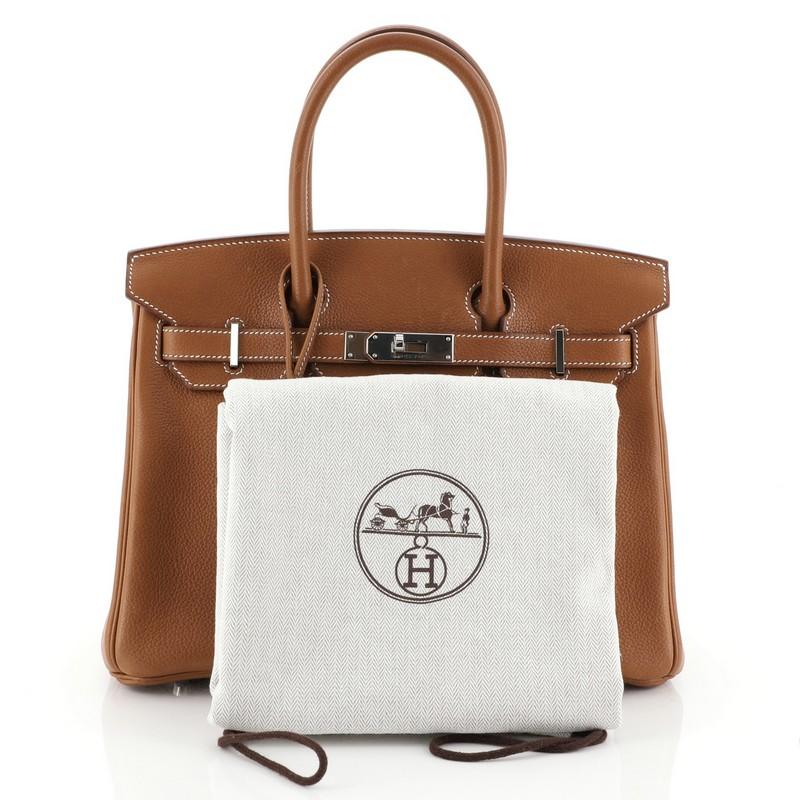 This Hermes Birkin Handbag Fauve Barenia Faubourg with Palladium Hardware 30, crafted in Fauve brown Barenia Faubourg leather, features dual rolled top handles, frontal flap, and palladium hardware. Its turn-lock closure opens to a Fauve brown