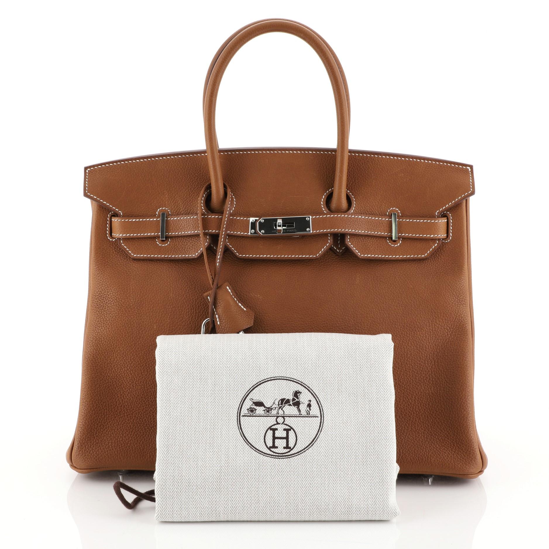 This Hermes Birkin Handbag Fauve Barenia Faubourg with Palladium Hardware 35, crafted from Fauve brown Barenia Faubourg leather, features dual-rolled top handles, frontal flap, and palladium hardware. Its turn-lock closure opens to a Fauve brown