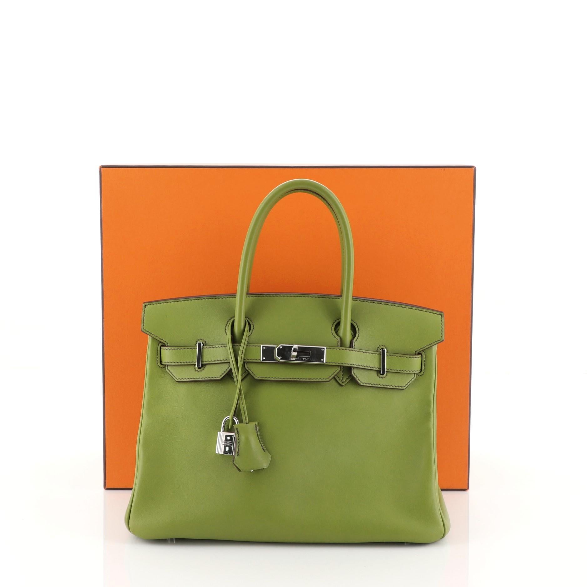 This Hermes Birkin Handbag Vert Anis Swift with Palladium Hardware 30, crafted in Vert Anis green Swift leather, features dual rolled top handles, frontal flap, and palladium hardware. Its turn-lock closure opens to a Vert Anis green Swift leather