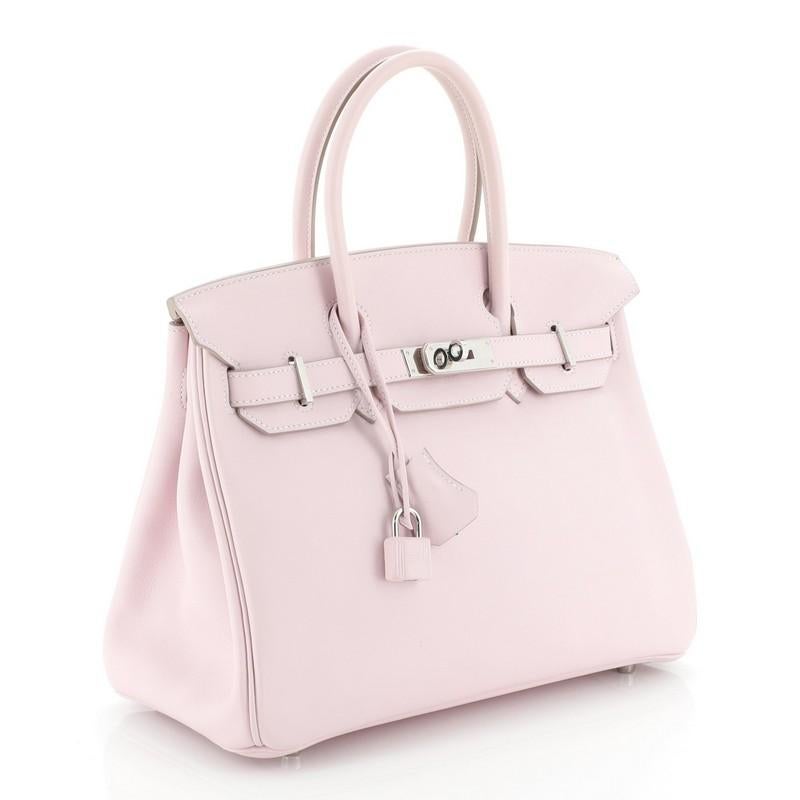 This Hermes Birkin Handbag Rose Dragee Swift with Palladium Hardware 30, crafted in Rose Dragee pink Swift leather, features dual rolled top handles, frontal flap, and palladium hardware. Its turn-lock closure opens to a Rose Dragee pink Swift