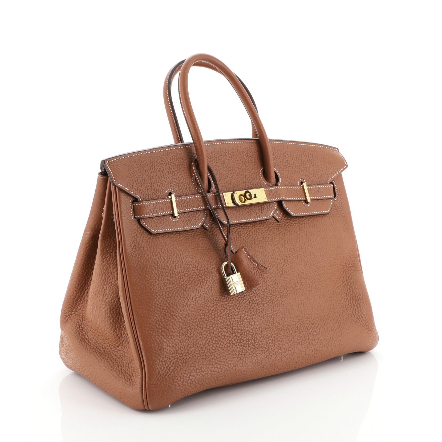 This Hermes Birkin Handbag Etrusque Clemence with Gold Hardware 35, crafted in Etrusque brown Clemence leather, features dual rolled handles, frontal flap, and gold hardware. Its turn-lock closure opens to a Etrusque brown Chevre leather interior