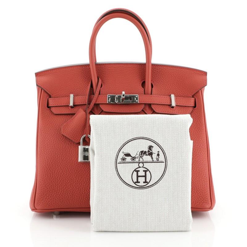 This Hermes Birkin Handbag Geranium Togo with Palladium Hardware 25, crafted in Geranium red Togo leather, features dual rolled handles, frontal flap, and palladium hardware. Its turn-lock closure opens to a Geranium red Chevre leather interior with
