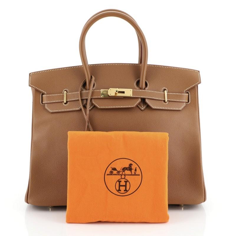 This Hermes Birkin Handbag Gold Courchevel with Gold Hardware 35, crafted in Gold brown Courchevel leather, features dual rolled top handles, frontal flap, and gold hardware. Its turn-lock closure opens to a Gold brown Chevre leather interior with