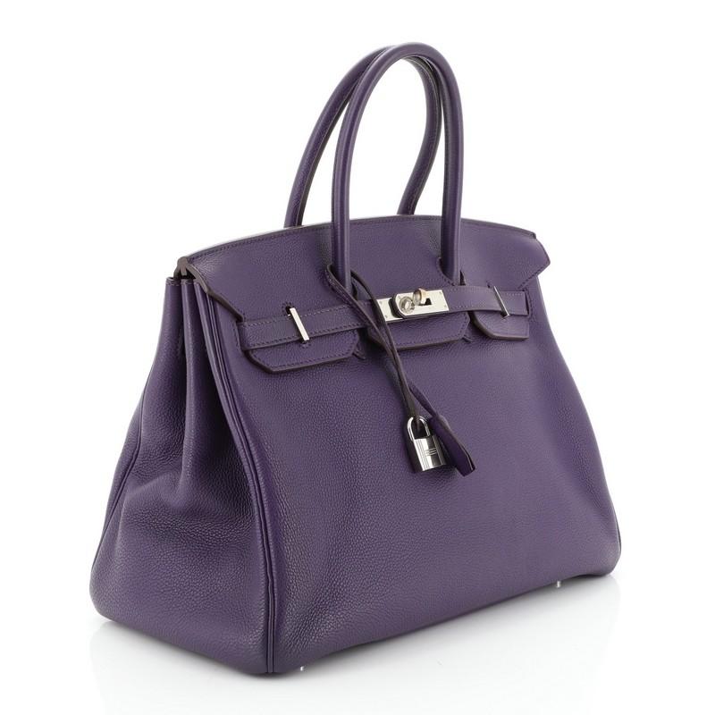 This Hermes Birkin Handbag Iris Togo with Palladium Hardware 35, crafted in Iris purple Togo leather, features dual rolled handles, frontal flap, and palladium hardware. Its turn-lock closure opens to an Iris purple leather interior with zip and