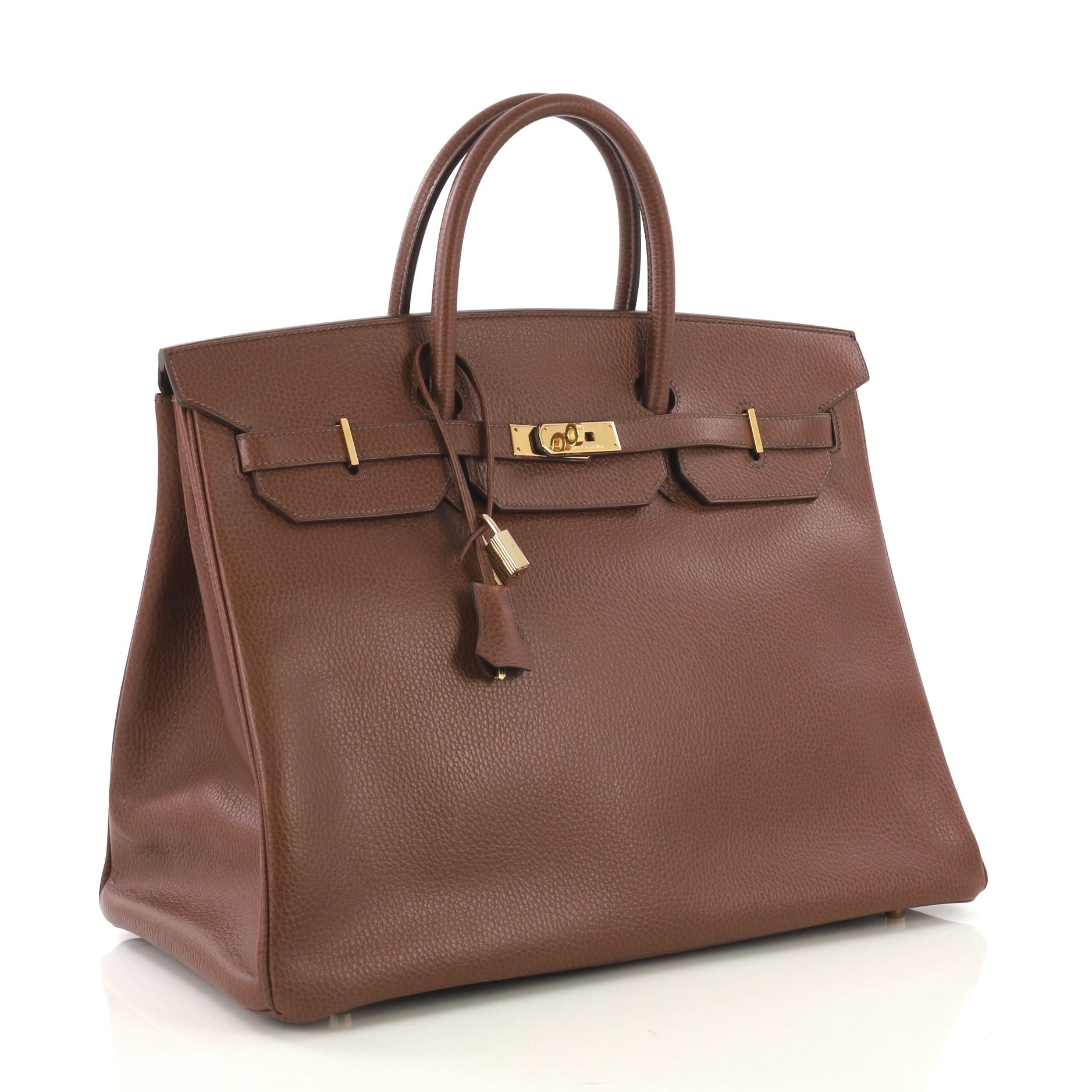 This Hermes Birkin Handbag Marron Fonce Ardennes with Gold Hardware 40, crafted in Marron Fonce brown Ardennes leather, features dual rolled handles, frontal flap, and gold hardware. Its turn-lock closure opens to a Marron Fonce brown Chevre leather