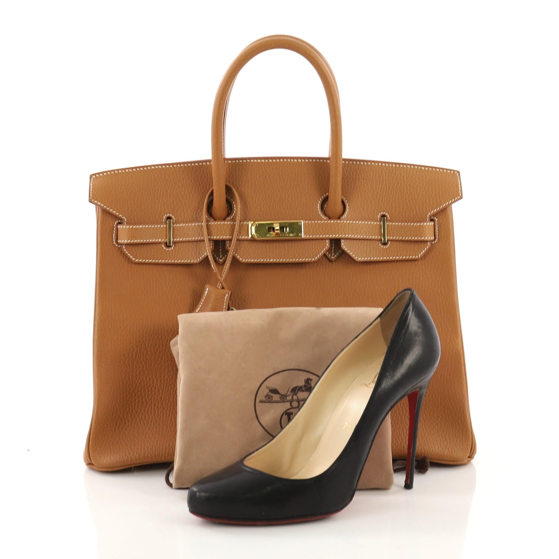 This Hermes Birkin Handbag Natural Ardennes with Gold Hardware 35, crafted in Natural brown Ardennes leather, features dual rolled handles, frontal flap, and gold hardware. Its turn-lock closure opens to a Natural brown Chevre leather interior with