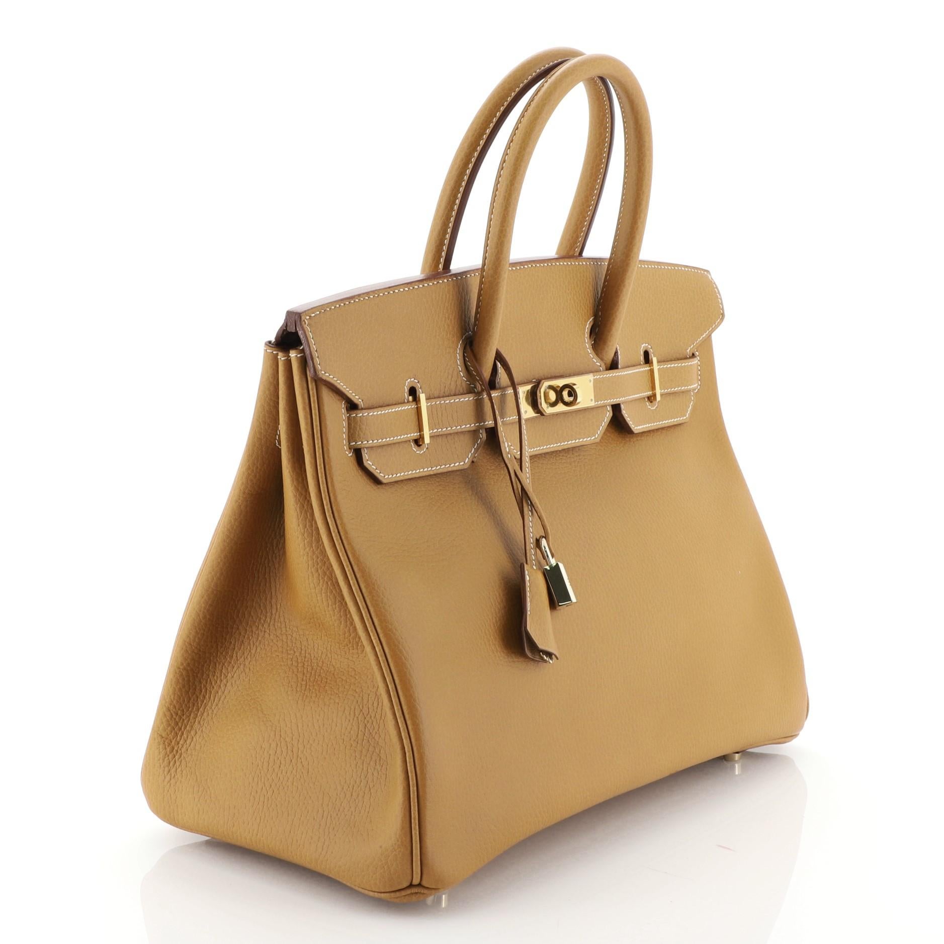 This Hermes Birkin Handbag Natural Ardennes with Gold Hardware 35, crafted in Natural brown Ardennes leather, features dual rolled handles, frontal flap, and gold hardware. Its turn-lock closure opens to a Natural brown Chevre leather interior with