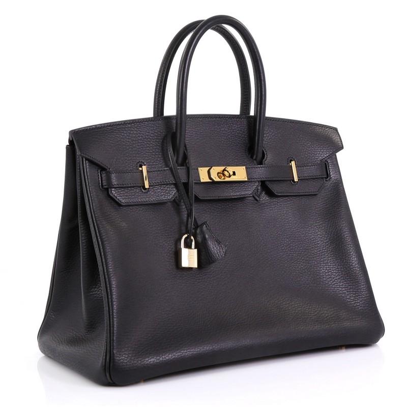 This Hermes Birkin Handbag Noir Ardennes with Gold Hardware 35, crafted in Noir black Ardennes leather, features dual rolled handles, frontal flap, and gold hardware. Its turn-lock closure opens to a Noir black Chevre leather interior with zip and