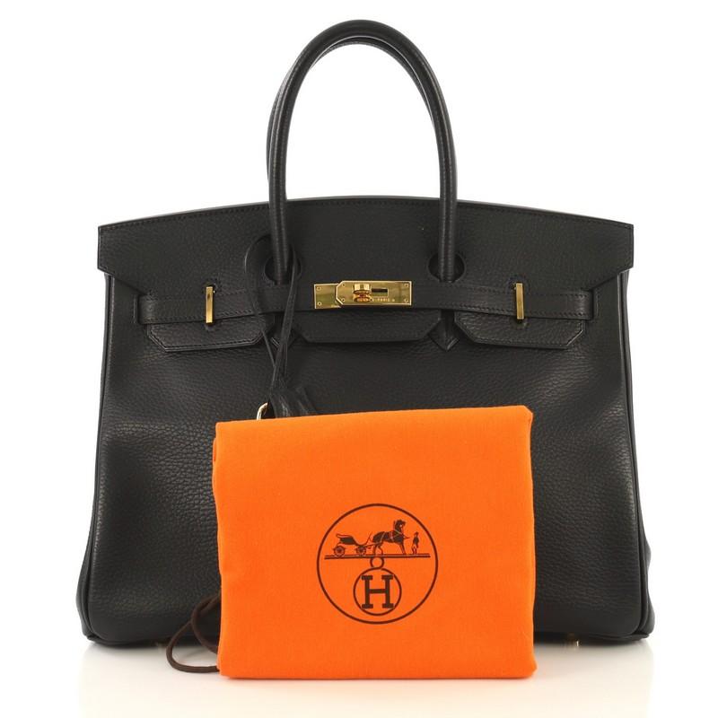 This Hermes Birkin Handbag Noir Ardennes with Gold Hardware 35, crafted in Noir black Ardennes leather, features dual rolled top handles, frontal flap, and gold hardware. Its turn-lock closure opens to a Noir black Chevre leather interior with zip