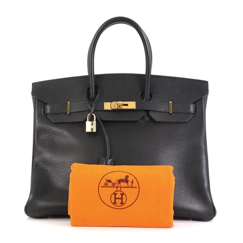 This Hermes Birkin Handbag Noir Ardennes with Gold Hardware 35, crafted in Noir black Ardennes leather, features dual rolled top handles, frontal flap, and gold hardware. Its turn-lock closure opens to a Noir black Chevre leather interior with zip