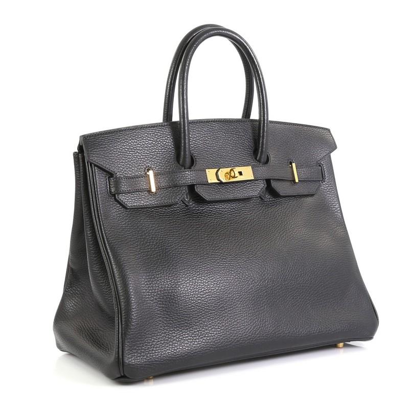 This Hermes Birkin Handbag Noir Ardennes with Gold Hardware 35, crafted in Noir black Ardennes leather, features dual rolled top handles, frontal flap, and gold hardware. Its turn-lock closure opens to a Noir black Chevre leather interior with zip
