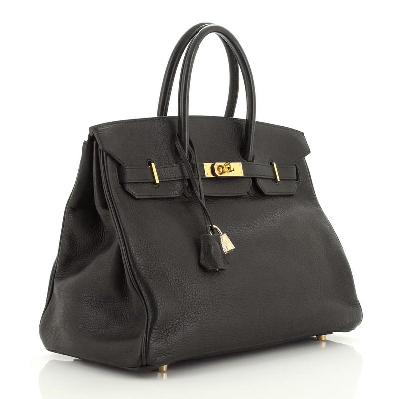 This Hermes Birkin Handbag Noir Buffalo Skipper with Gold Hardware 35, crafted in Noir black Buffalo Skipper leather, features dual rolled handles, frontal flap, and gold hardware. Its turn-lock closure opens to a Noir black Buffalo Skipper leather
