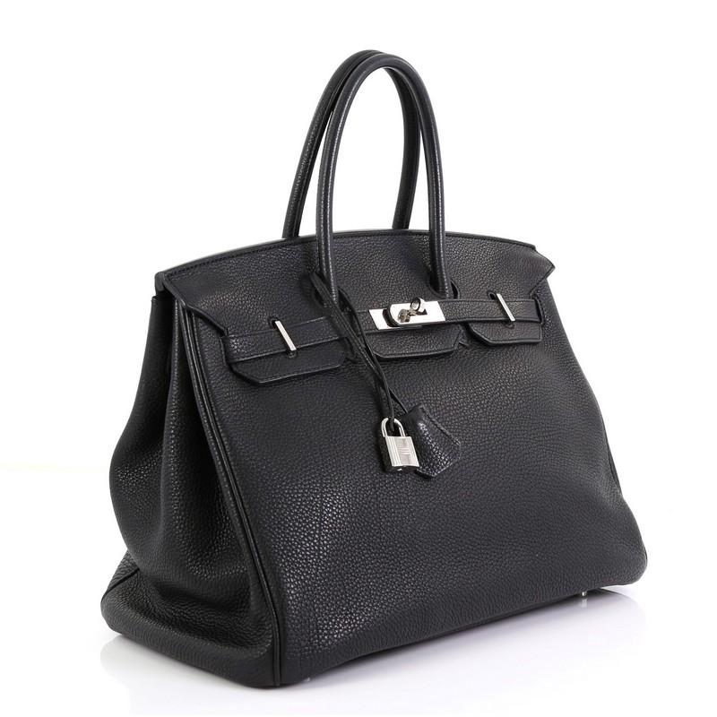 This Hermes Birkin Handbag Noir Togo with Palladium Hardware 35, crafted in Noir black Togo leather, features dual rolled handles, frontal flap, and palladium hardware. Its turn-lock closure opens to a Noir black Chevre leather interior with zip and