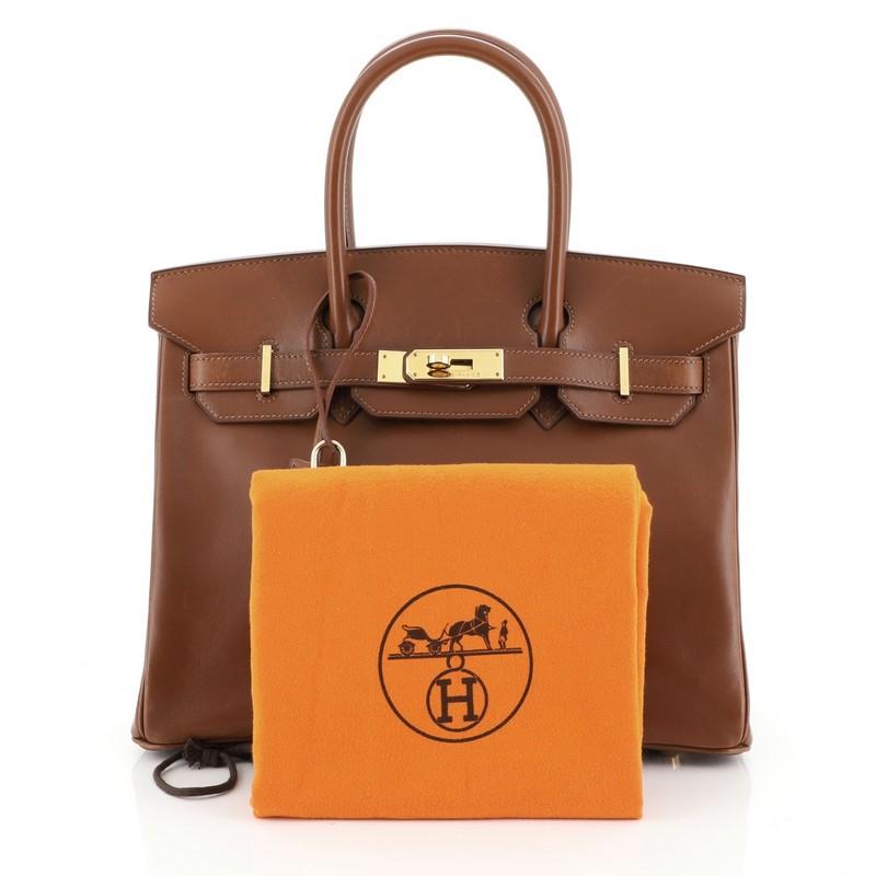 This Hermes Birkin Handbag Noisette Box Calf with Gold Hardware 30, crafted in Noisette brown Box Calf leather, features dual rolled handles, front flap and gold-tone hardware. Its turn-lock closure opens to a brown leather interior with zip and