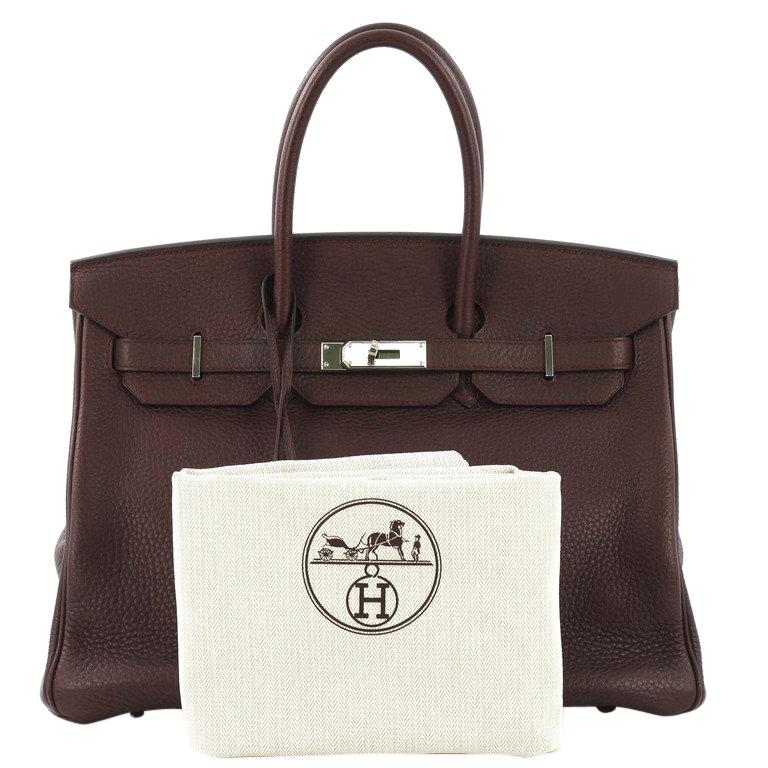 This Hermes Birkin Handbag Prune Clemence with Palladium Hardware 35, crafted in Prune purple Clemence leather, features dual rolled handles, frontal flap, and palladium hardware. Its turn-lock closure opens to a Prune purple Chevre leather interior