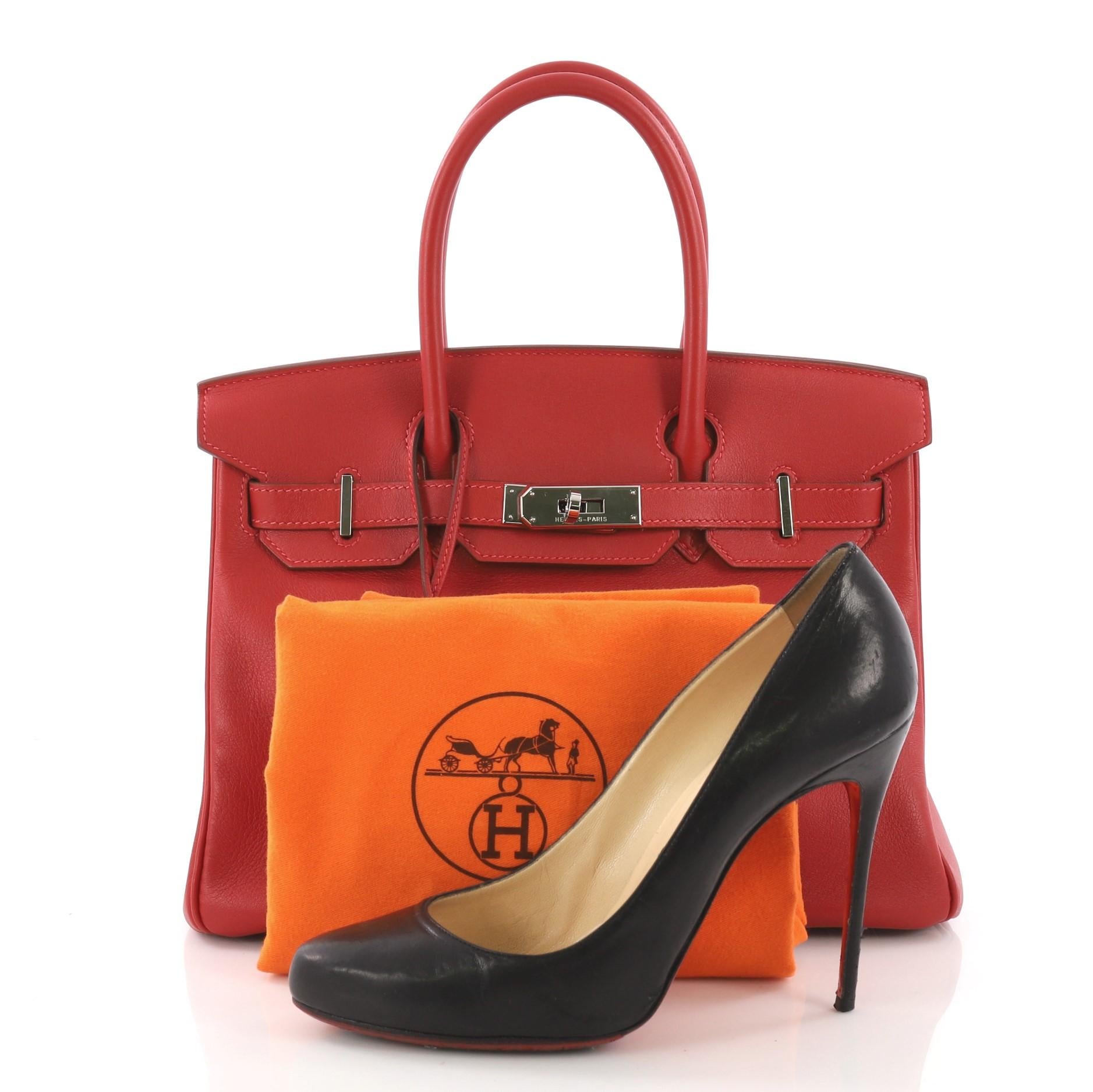 This Hermes Birkin Handbag Rouge Vif Swift with Palladium Hardware 30, crafted in Rouge Vif red swift leather, features dual rolled handles, front flap and palladium-tone hardware. Its turn-lock closure opens to a red leather interior with slip and